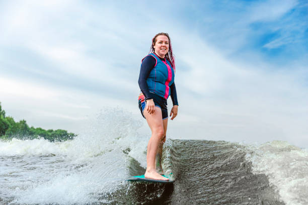 młoda kobieta wakesurfing w dół fal rzeki - wakeboarding motorboating extreme sports waterskiing zdjęcia i obrazy z banku zdjęć