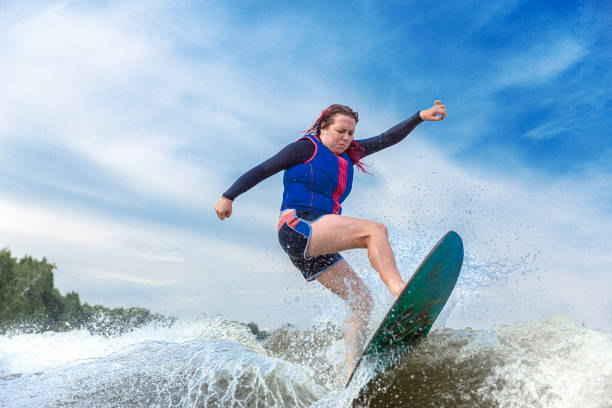 mulher nova que surfa pelas ondas do rio - wakeboarding motorboating extreme sports waterskiing - fotografias e filmes do acervo