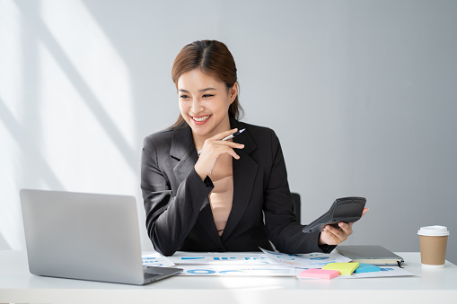 Young serious accountant working for her client, focusing on her work at office desk.