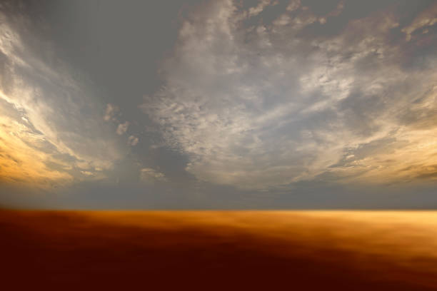 istock Sky and brown ground background with clouds and rays of light shining through. 1498307455