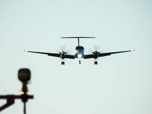 A NSW Ambulance Beech King Air 350C plane, registration VH-8AM, on her landing approach from the north of Sydney Kingsford-Smith Airport as flight AM260 from Newcastle, passing over structures of navigational landing lights. The headlight appears in the shape of a heart.  This image was taken from near Nigel Love Bridge, Mascot under the flight path at the northern end of the runway on a sunny, winter afternoon on 10 June 2023.