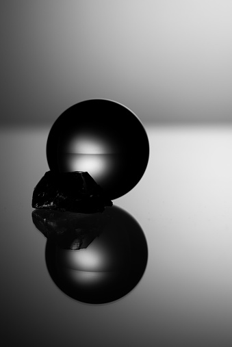A glass ball and crystal on a reflective surface