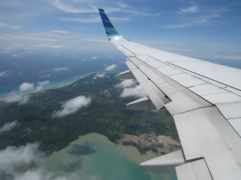 Wing of an airplane flying above the sea, view from the window