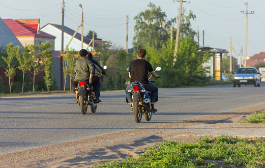 Uralsk, Kazakhstan (Qazaqstan), 17.03.2017 - riding a motorcycle in the city. Young people ride motorcycles without license plates. Riding a motorcycle without a helmet.