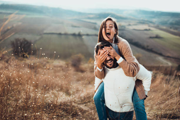 istock Young playful couple having fun while piggybacking in autumn day on a hill. 1498324445