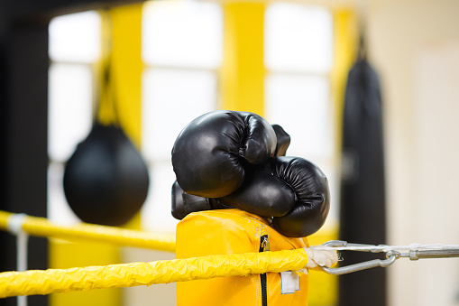 Ringside Black Boxing gloves in a boxing ring with ropes on yellow boxing pads in a boxing gym no people, Cape Town, South Africa