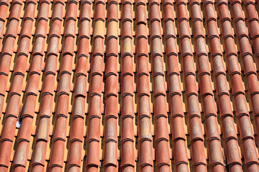 Orange colored tiles a bit weathered on roof top in the sun, full frame, abstract backgrounds