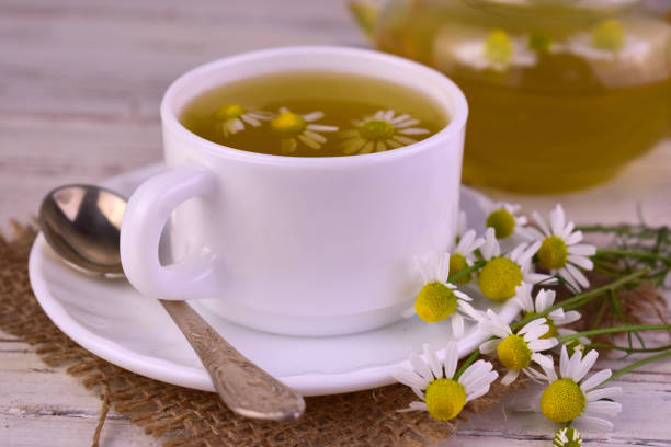 istock Medicinal chamomile tea in a cup on a white wooden background. 1498328680
