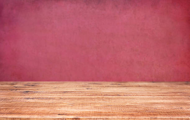 istock Wooden table top on grunge pink wall background 1498334292