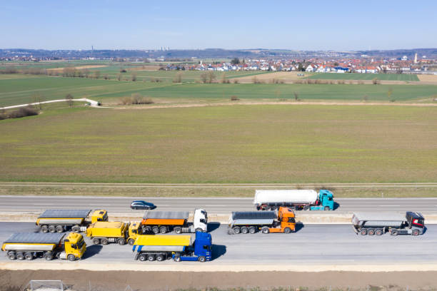 Drivers waiting to unload the fresh and hot asphalt mix on the prepared asphalt paving machine.