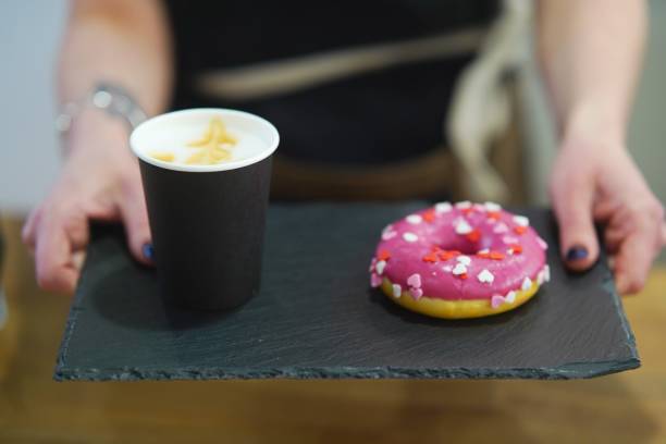 istock Barista holds out a tray with a donut and coffee. 1498337225