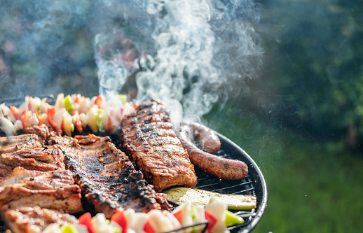 Close-up of barbecues steaks and vegetables on the charcoals grill.