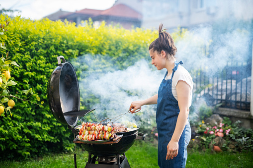 Woman preparing grilled food for a barbeque garden party.