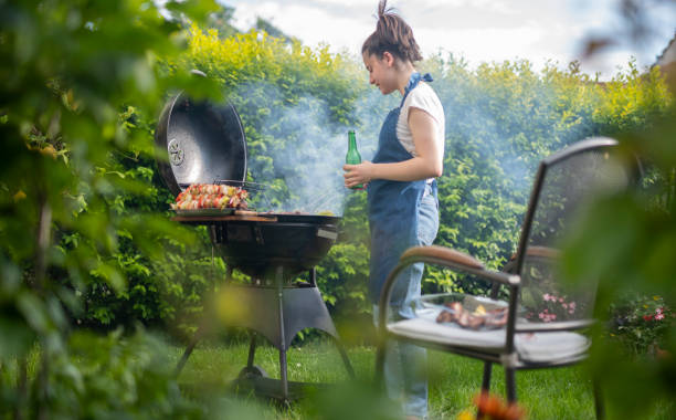 istock Young woman cooking dinner on barbecue grill at back yard. 1498342500