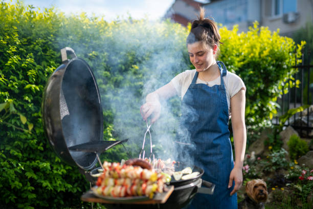 istock Young woman cooking dinner on barbecue grill at back yard. 1498342528