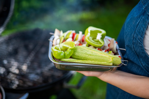 Unrecognizable woman putting vegetables on the barbeque.
