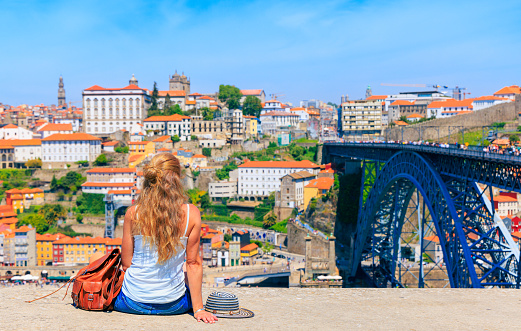 Woman tourist enjoying landscape on the old town with river and famous bridge in Porto city- Portugal