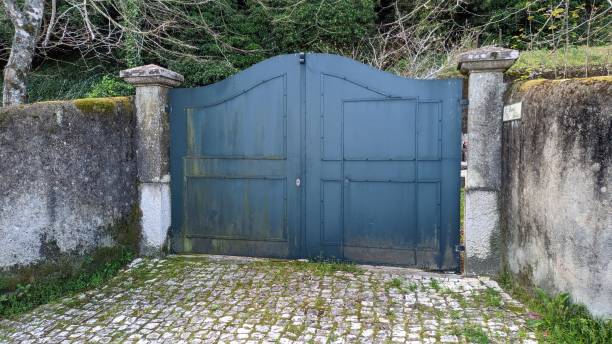istock An old stone fence trimmed with plaster and overgrown with moss between two pillars of concrete, a gray iron gate 1498349971
