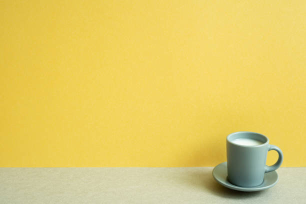 istock Cup of milk on gray table. yellow wall background. copy space 1498353082
