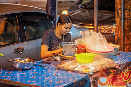 Bangkok, Thailand - March 26th 2023: Woman working in a street kitchen in the center of the capital of Thailand