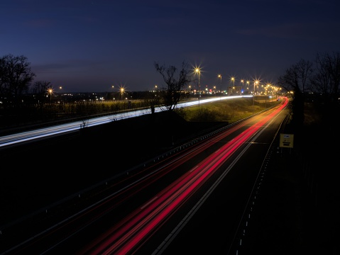 A nighttime highway illuminated by glowing light trails on the asphalt. Tegelen, Netherlands.