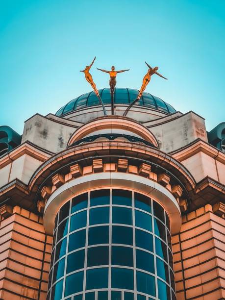 London, United Kingdom – February 06, 2022: An ornate building with gold statues adorning the rooftop against a backdrop of bright blue sky