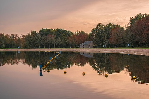 A tranquil lake illuminated by the orange glow of a setting sun, with several spheres floating on the surface