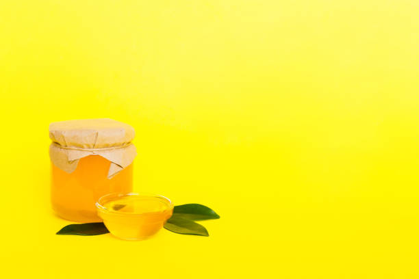 istock Honey in jar with leaves and honey dipper on colored background top view with copy text 1498361149