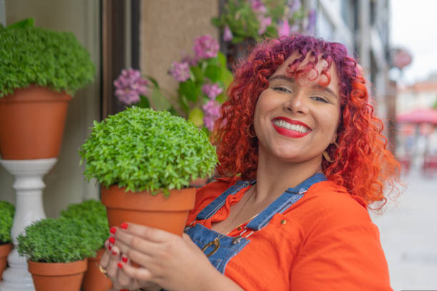 ストリートショップでマンジェリコ植物を持つ若い大人のフェメレ - portuguese culture women ethnic smiling ストックフォトと画像