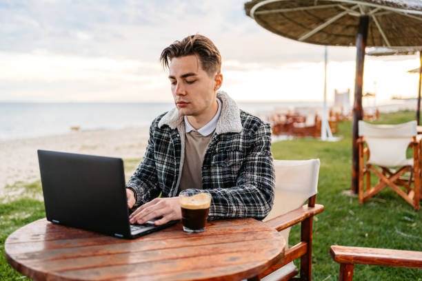 istock Young Man Working On Laptop In A Beach Bar In Greece 1498365562