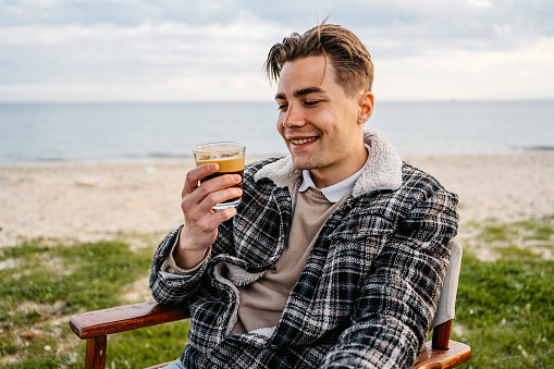 Handsome young man drinking coffee in a beach bar in Nea Flogita, Greece.