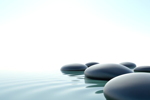 some zen stones on water on a white background
