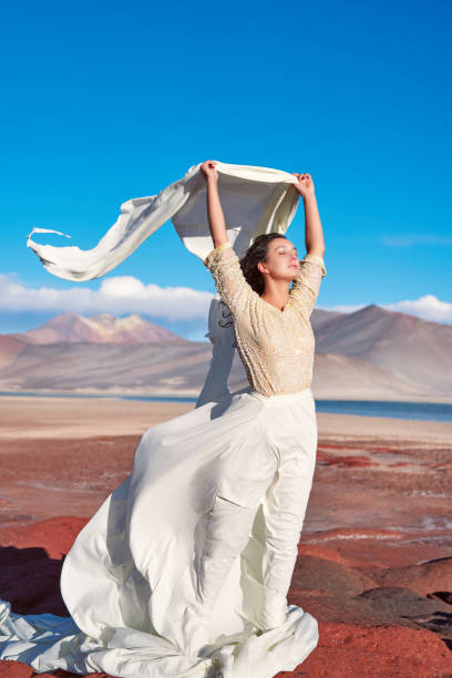 konzeptuelles künstlerisches porträt einer frau mit weißen stoffen im wind, die sich in der altiplano-wüste von san pedro de atacama auf dem kopf hält - mount misen stock-fotos und bilder