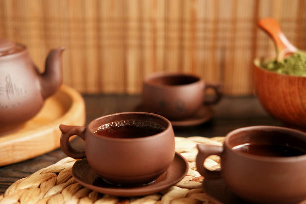 Tea Ceremony. Traditional Asian Tea Utensil, Serving Authentic Set. Person Pouring Tea from Brown Pottery Teapot to Teacup. Bamboo Tray. Lifestyle. Wellness Balance Health. Tea Brewing Equipment. Tea master. Dark mood. Japan. China. Serves chashaku. ceremonia del té. utensilios de té asiático tradicional, que sirve un conjunto auténtico. persona vertiendo té de tetera de cerámica marrón a taza de té. bandeja de bambú. modo de vida. wellness balance health. equipo de preparación de té