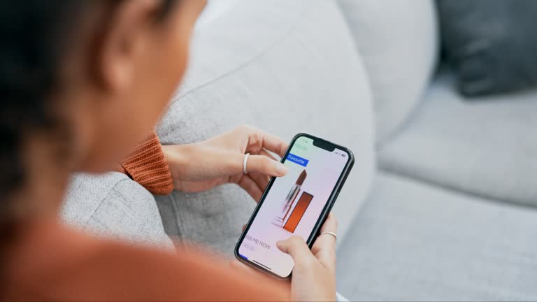 Woman, hands and phone for online shopping, makeup cosmetics or beauty products on living room sofa at home. Hand of female searching for purchase, store or lipstick on smartphone app in ecommerce