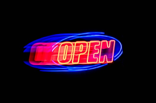 A vibrant neon OPEN sign with a blurred effect on a dark background