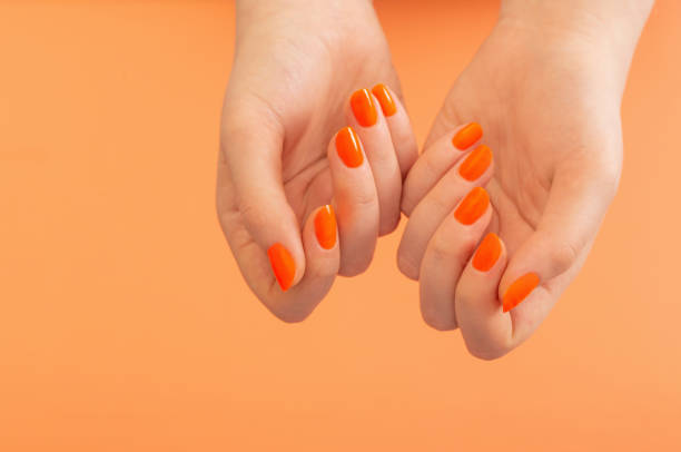istock female hands with orange manicure   on  orange background 1498380657