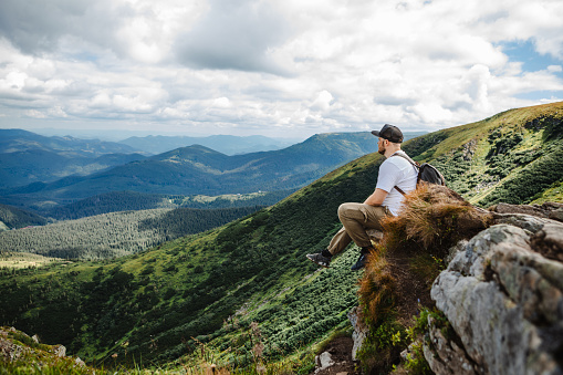 Man on top of Mountain sitting on Rock