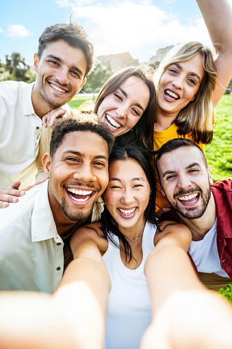 Multiracial young people taking selfie pic with smart mobile phone device - Vertical photo of happy friends smiling at camera - Life style concept with guys and girls hanging out on summer day
