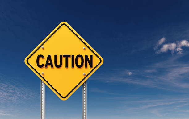 Caution written yellow off road traffic sign before blue sky. Horizontal composition with copy space.
