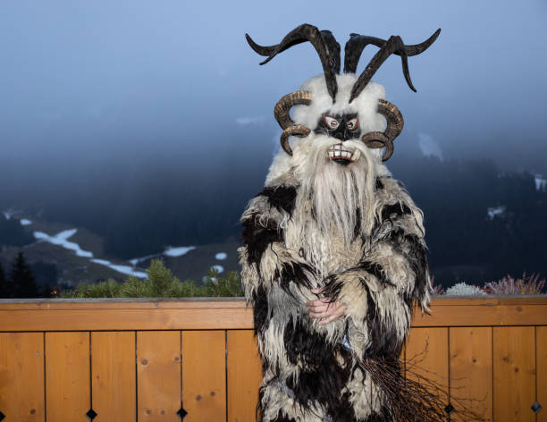 krampus, le héros des légendes de noël, vêtu d’une peau et d’un masque à cornes se tient près d’une clôture en bois, autriche, gastein - mythology snow winter austria photos et images de collection