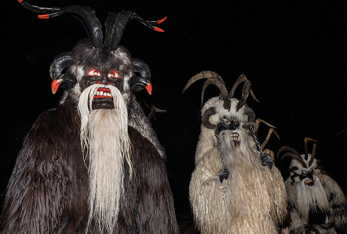 Three men in costumes of the legendary Christmas Krampus in animal skins with horns on their heads, Austria, Gastein. High quality photo
