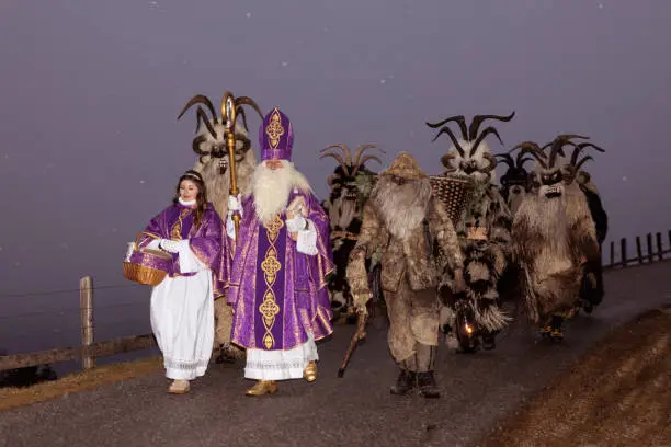 Christmas procession of St. Nicholas and Krampus on a rural road at dusk under the snow, Austria, Gastein. High quality photo