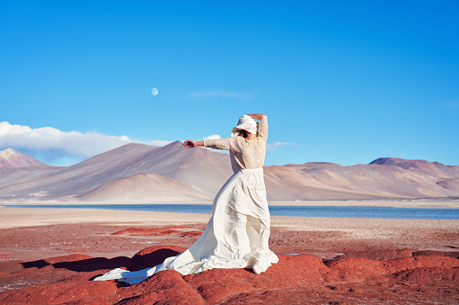 abstract portrait woman with long dress and face covered with cloth on red stones in the desert highlands