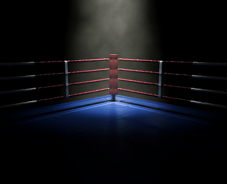 A dimly spotlit corner of a boxing ring surrounded by ropes on a dark isolated background - 3D render