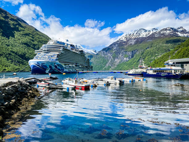 Geiranger, Norway-May 30, 2023  -The NCL cruise ship Prima is anchored at the end of the Geiranger Fjord alongside fjord tour boats and smaller private water craft.