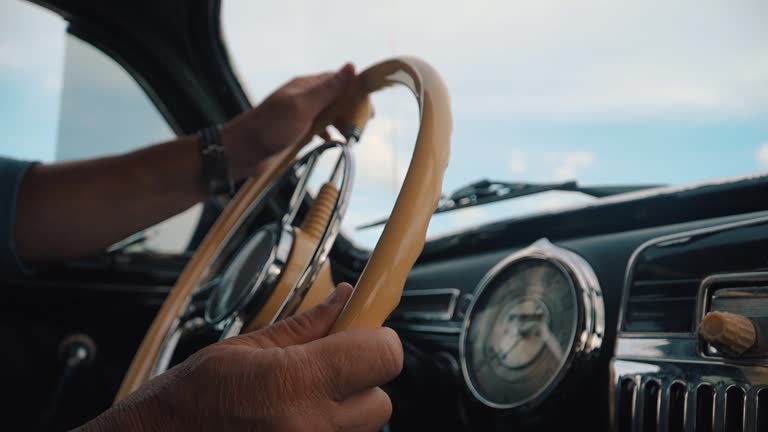 Man driving retro car. Male hands holding steering wheel of vintage car