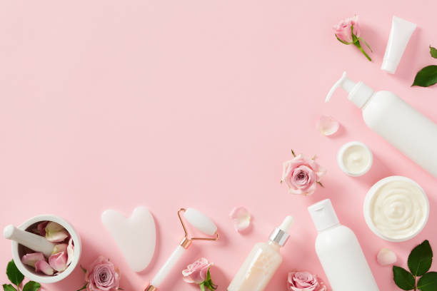 istock Face care routine concept. Natural cosmetics with quartz roller, gua sha, and rose blossoms on pastel pink background 1498402642