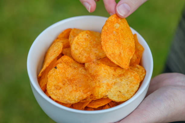 istock Salted pepper potato chips close-up in a white bowl held in hands 1498404063