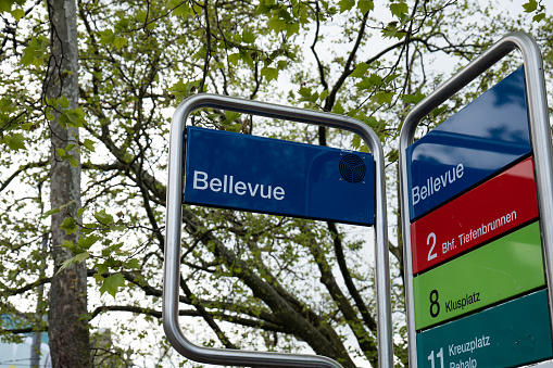 Bus and tram stop street sign at Bellevue, Zurich, Switzerland. Low angle view, cloudy sky, no people.